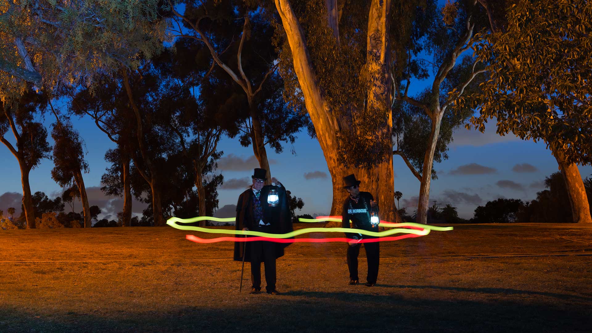 san Diego haunted forest at night with two ghost hosts standing and holding lanterns while two orbs encircle them