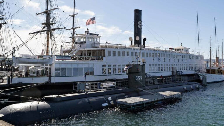 The LSS Dolphin submarine floating parallel with a large ship called the Berkeley