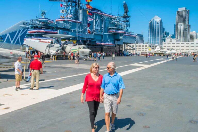 couple walking hand in hand at uss midway museum