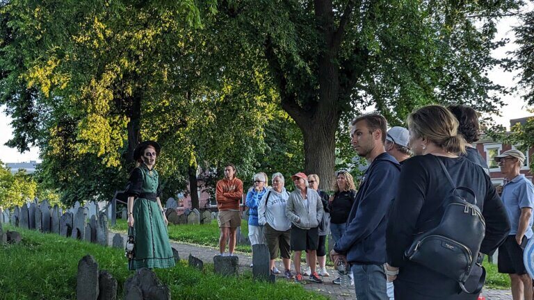 Ghosts & Gravestones Nightwalk tour guide and guests at burying ground