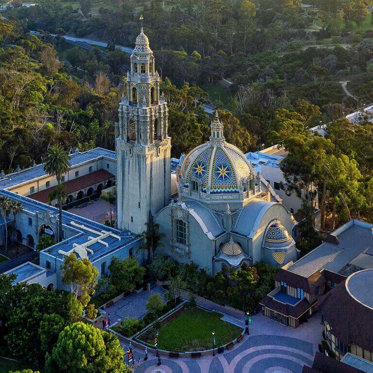 A vibrant view of Balboa Park showcasing lush gardens, historic architecture, and visitors enjoying the sunny day.