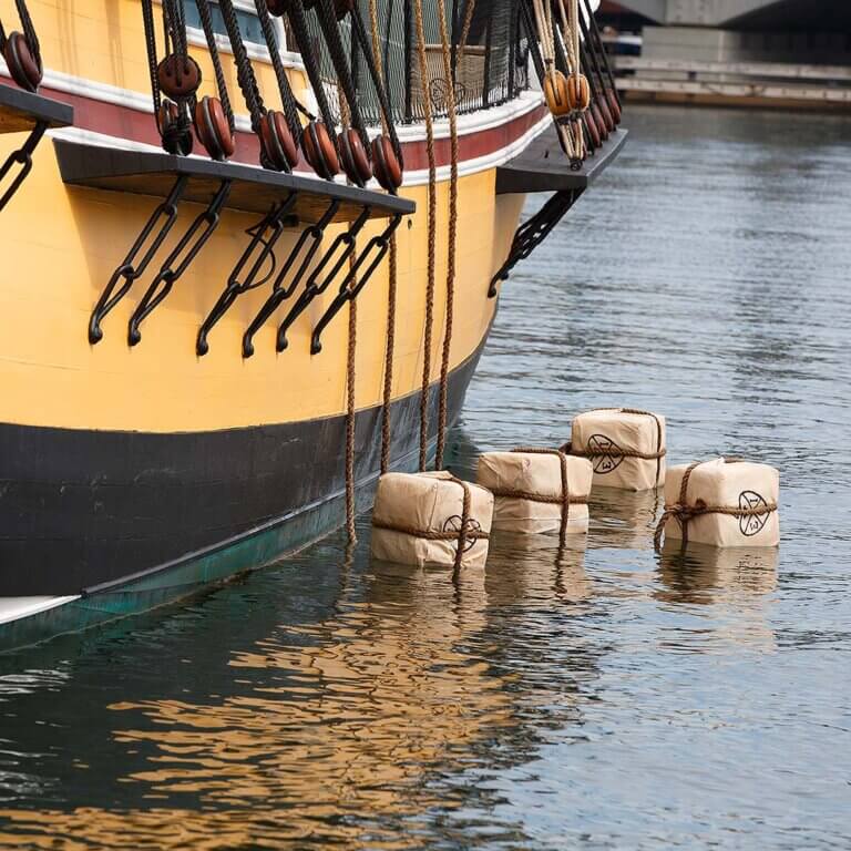boston tea party ship and tea chests floating on top of the water